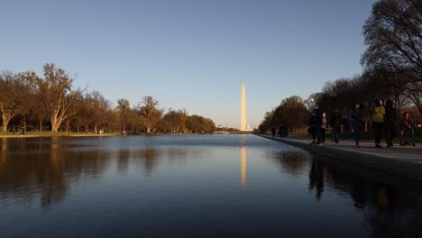 Time-lapse-view-of-crowds-walking-beside-the-reflecting-pool-in-Washington,-DC,-USA-with-the-Washington-Monument-in-the-distance-and-reflection-in-calm-water