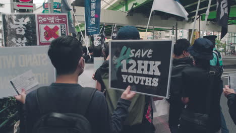 Demonstrators-Holding-Save-12-HK-Youths-Placard-In-Tokyo-Japan---Solidarity-With-Hong-Kong-Protest---medium-shot,-back-view