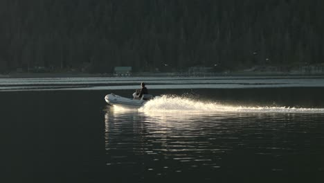 Man-in-Motorboat-Sailing-in-Sea-Lagoon-Near-Alaskan-Coast-on-Sunny-Evening,-Slow-Motion-Wide-View
