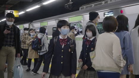 Zwei-Studentenkinder,-Die-Während-Der-Corona-virus-pandemie-In-Tokio,-Japan,-Mit-Gesichtsmaske-Aus-Dem-Zug-Aussteigen