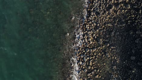 A-high-revealing-drone-video-looking-down-at-the-raw-rocky-coastline-of-the-small-town-of-Bargara-located-in-the-region-of-Bundaberg-Queensland-Australia