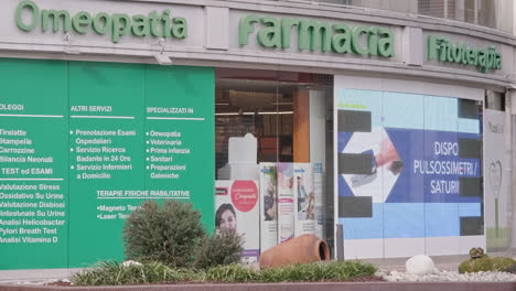 Homeopatía-Italiana,-Farmacia,-Fitoterapia,-Vista-Frontal-Desde-El-Exterior-Con-Publicidad-En-Pantalla-Destacada