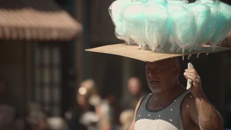 Street-vendor-balancing-cotton-candy-on-his-head-during-parade,-Slow-Motion