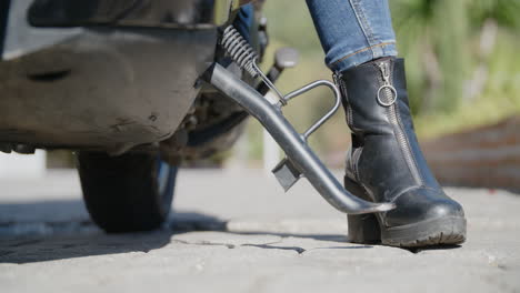 Close-up-of-woman's-black-boot-pushing-the-scooter-off-of-the-stand