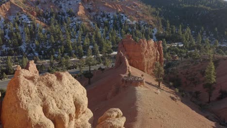 A-drone-shot-of-the-sandstone-rocks-of-Red-Canyon-area-near-Bryce-Canyon-in-the-winter-and-a-van-is-seen-driving-on-the-below