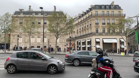Cars,-motorcycles,-and-pedestrians-walking-along-the-Champs-Élyseés-Avenue-a-few-meters-from-the-Arc-de-Triomphe