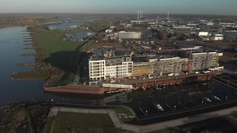 Floodplains-and-contemporary-new-luxury-apartment-building-under-construction-next-to-recreational-pleasure-port-with-industrial-are-behind-on-a-sunny-day-along-the-river-IJssel