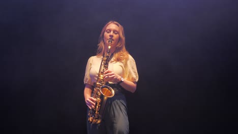 Young-Caucasian-Woman-Playing-Solo-on-Saxophone-Under-Stage-Lights-in-Haze