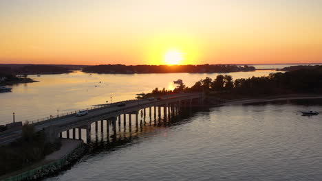 Stunning-sunset-over-a-bridge-in-Sag-Harbor,-Hamptons,-New-York,-Aerial-shot