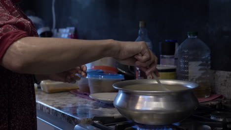 Ethnic-Minority-Woman-Stirring-Food-In-Steel-Pot-On-Cooker