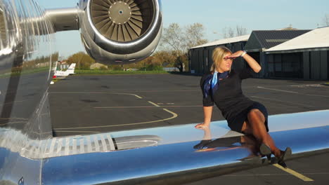 A-playful-flight-attendant-sits-on-the-wing-of-an-aircraft