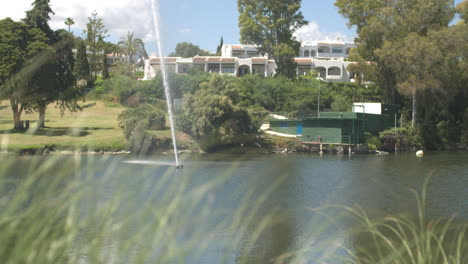 Footage-of-a-water-fountain-shooting-up-water-in-slow-motion-in-a-pond-at-a-golf-course-in-Marbella,-Spain