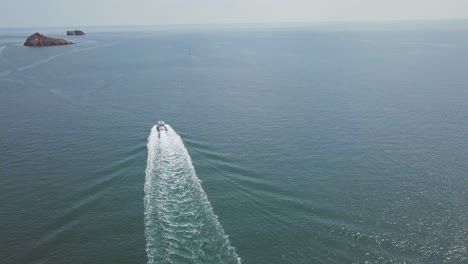 Drohnenaufnahmen-Eines-Seefahrenden-Motorboots,-Das-Auf-Der-Oberfläche-Eines-Ozeans-Nahe-Der-Küste-Fährt