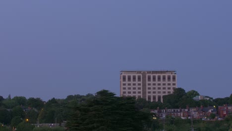 Dusk-to-dawn-timelapse-of-an-Office-building-surrounded-by-a-suburban-area,-and-lots-of-trees