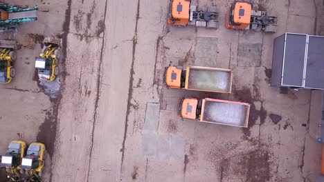 Aerial-shot-of-bulldozer-and-trucks-in-outside-warehouse