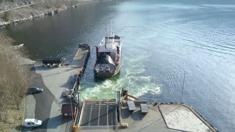 Toma-Descendente-De-Un-Dron-De-Un-Ferry-Preparándose-Para-Descargar-Automóviles-En-Un-Muelle-En-Un-Fiordo-En-Noruega