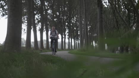 Young-Healthy-Woman-Cycling-Home,-Through-Beautiful-Woodland