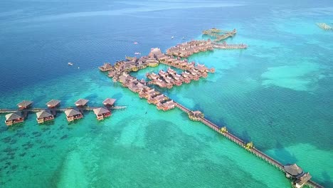 Aerial-flight-over-crystal-clear-water-and-resort-in-Malaysia,-steady-long-distance-shot-in-slow-motion