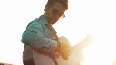 Golden-hour-cinematic-sunset-musician-playing-guitar-in-field