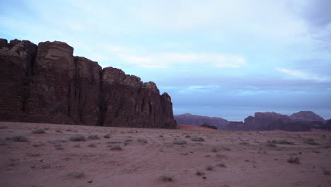 Eine-Panoramaaufnahme-Der-Wüstenschlucht-Wadi-Rum-Mit-Sand,-Bergen-Und-Weißen-Wolken-Im-Hintergrund