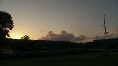 Eine-Sonnenuntergangslandschaft-Mit-Leichten-Wolken,-Einem-Silhouettierten-Baum-Auf-Der-Linken-Seite-Und-Gelegentlich-Vorbeifliegenden-Vögeln
