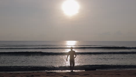 Mann,-Der-Bei-Sonnenaufgang-In-Asien-In-Richtung-Ozean-Geht,-Um-Morgens-Schwimmen-Zu-Gehen