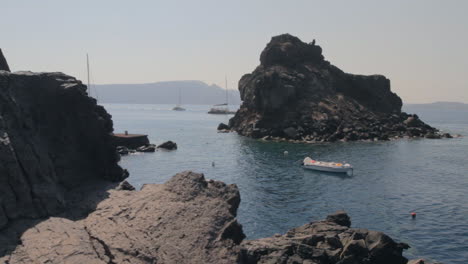 Ein-Felsiger-Strand-In-Der-Caldera-Von-Santorini,-Um-Den-Herum-Katamarane-Schwimmen