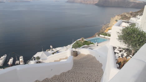Looking-down-at-the-cliffs-and-holiday-villas-that-engulf-the-Aegean-sea-in-Oia,-Santorini