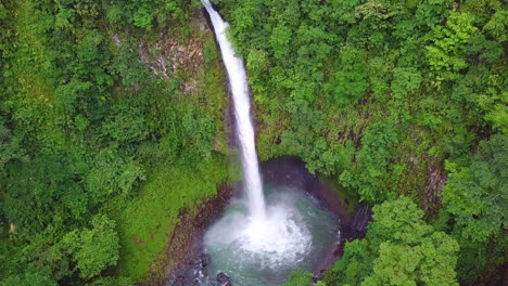 La-Fortuna-Waterfall-crashing-into-turquoise-pool-in-Costa-Rica-jungle,-AERIAL-PAN