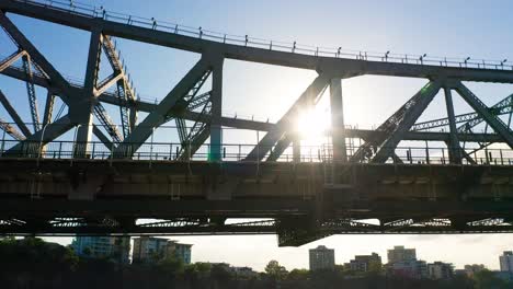 Silhouette-of-a-cyclist-travelling-across-a-large-bridge-with-the-sun-behind