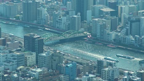 Aerial-view-of-Tokyo-river-and-ferry-crossing-under-the-bridge-from-Skytree-tower