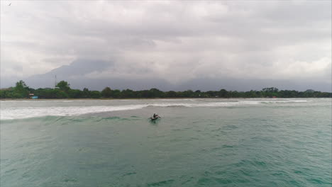 AERIAL:-Slow-motion-Honduran-fisherman-on-canoe-paddling-towards-the-beach---El-Porvenir,-Honduras-2