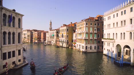 A-lot-of-traffic-and-some-typical-Gondolas-on-the-famous-Canale-Grande,-the-main-canal-in-Venice,-seen-from-the-iconic-Rialto-Bridge