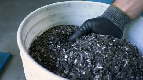 Gloved-hand-picks-up-metal-flakes-at-metal-recycling-plant
