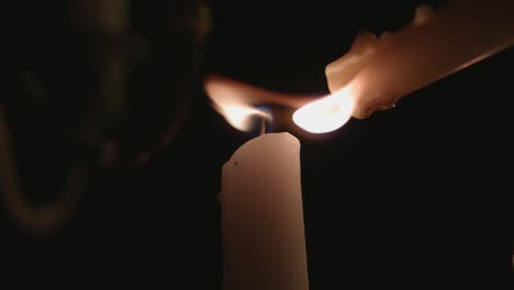 A-lone-white-candle-being-lite-by-another-candle-in-slow-motion
