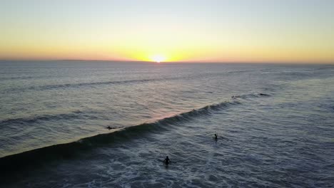 Aerial-people-surfing-during-sunset-golden-hour-on-Cape-town-beach