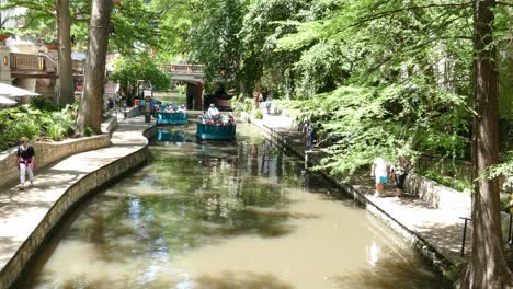 Electric-boat-with-tourists-on-coming-up-the-canal-in-San-Antonio-Riverwalk