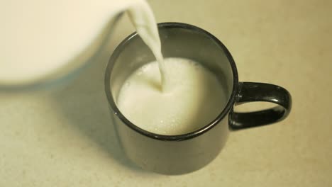 Overhead-Shot-of-Steaming-Hot-Milk-Being-Poured-into-a-Black-Mug