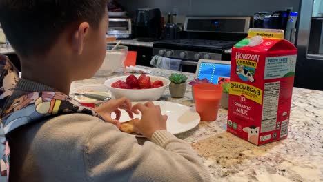Junge-Isst-Morgens-Frühstück-Mit-Einer-Tasse-Bio-Milch-Von-Horizont,-Um-Ihn-Für-Einen-Anstrengenden-Schultag-Zu-Starten