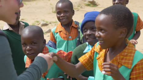 Niños-De-Una-Escuela-Primaria-En-África-Estrechan-Alegremente-La-Mano-De-Un-Visitante-Caucásico