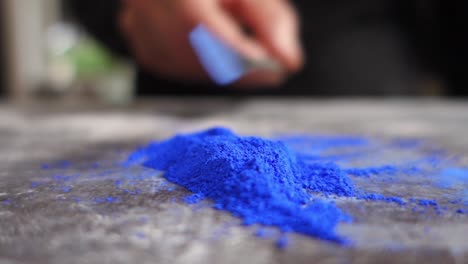 Artist-prepering-blue-powder-pigment-on-table-in-workshop,-closeup