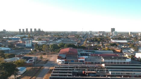A-pull-down-drone-shot-of-Industry-buildings-in-the-outskirts-of-Bulawayo,-Zimbabwe-at-sunset