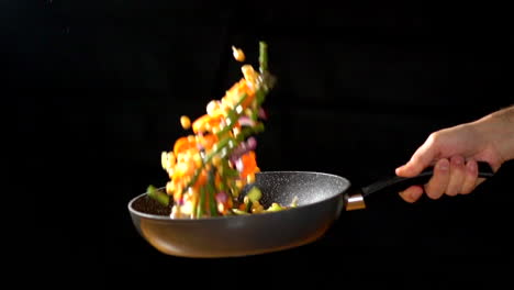 CU-SLOWMOTION:-Chef-holding-Wok-while-tossing-vegetables-in-a-studio-lighting