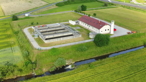 Aerial-view-of-small-sewage-treatment-plant-with-wastewater-tanks-and-filters,-fields-with-crops-surrounding-the-plant,-Slovenska-Bistrica,-Slovenia