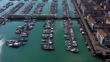Aerial-push-over-Brighton-Marina,-pan-down-to-moored-sail-boats---yachts