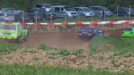 Autocross-cars-compete-in-amateur-racing-on-the-dirt-track-in-sunny-summer-day,-flat-out-cornering,-medium-shot-from-a-distance