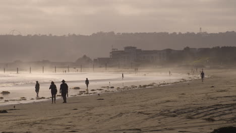 People-Walk-In-The-Surf-On-Coronado,-California,-Beach-At-Sunset