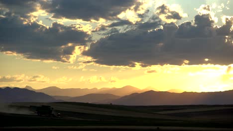 Combine-harvester-in-rural-Colorado,-against-a-background-of-mountains-and-sunset