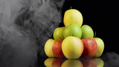 Smoke-covering-pile-of-ripe,juicy-apples-with-water-droplets-on-them