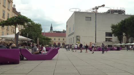 Establishing-static-view-of-Museumsquartier-in-Vienna,-with-typical-chairs-and-people-walking